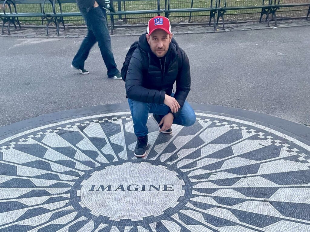 Kiss Ákos a New York-i Central Parkban található, John Lennon emlékére létrehozott Strawberry Fields-en, annak is a közepén található Imagine mozaiknál